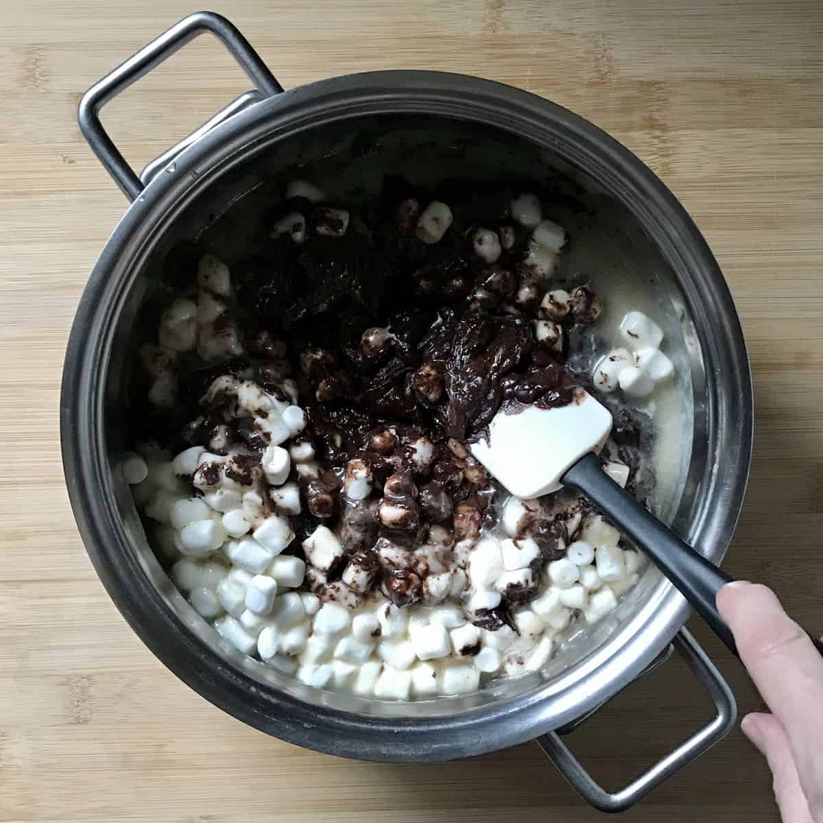Mini marshmallows and chocolate chips are stirred to make fudge.