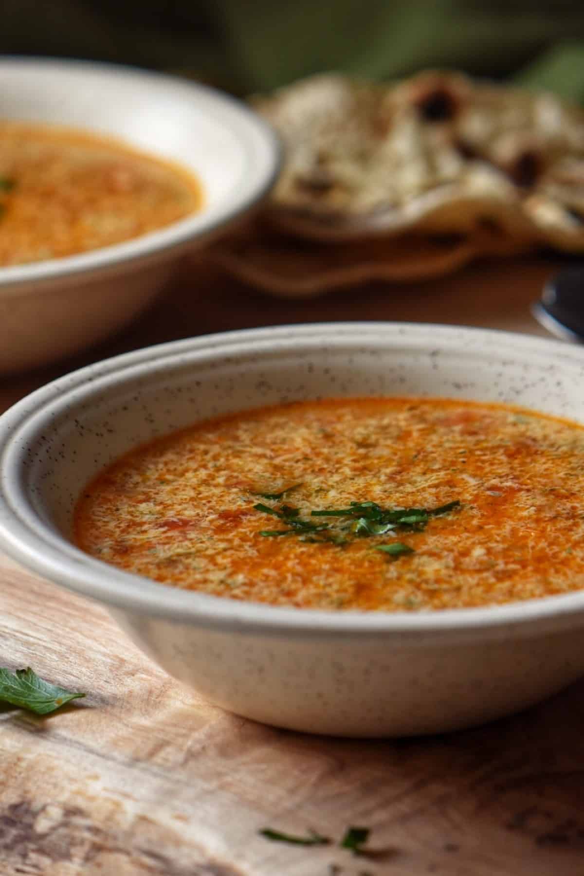 A bowl of Italian Egg Drop Soup on a wooden board.