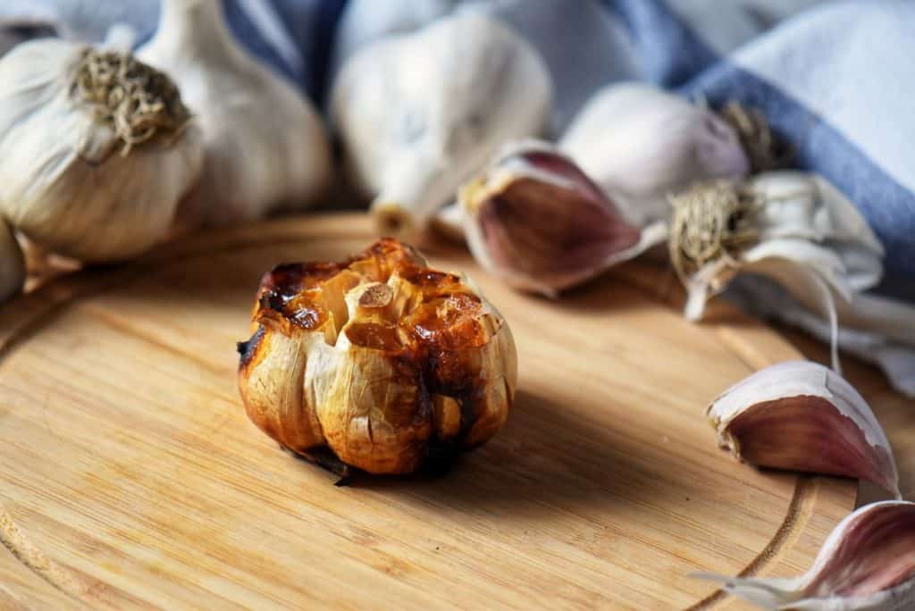 A caramelized garlic head on a wooden board.