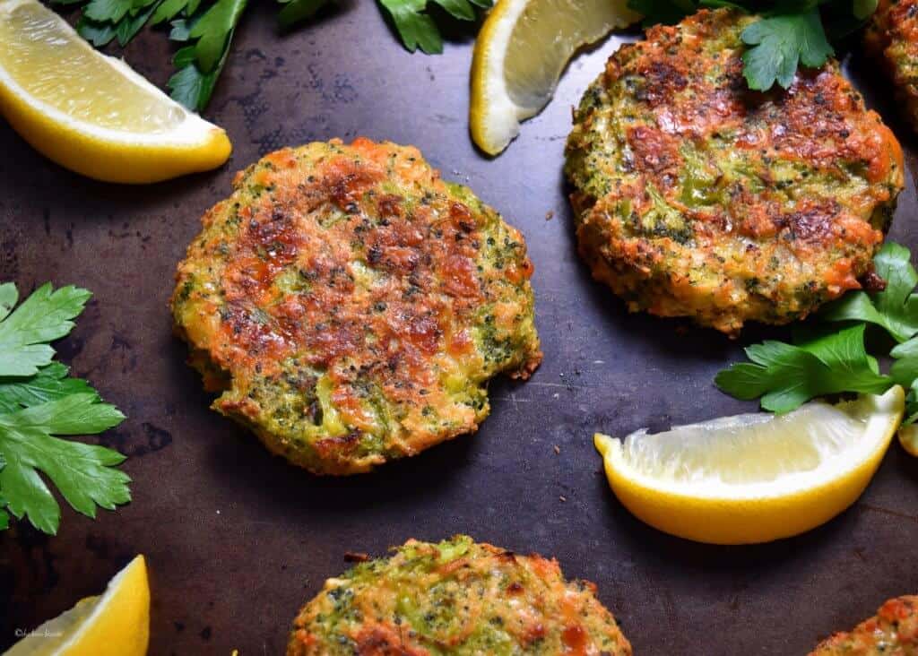 Broccoli fritters surrounded by lemon wedges. 