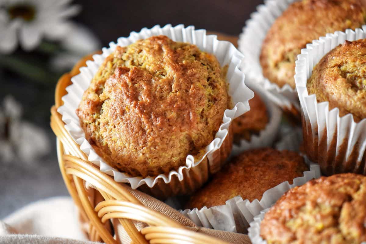 Freshly baked healthy orange muffins in a wicker basket.