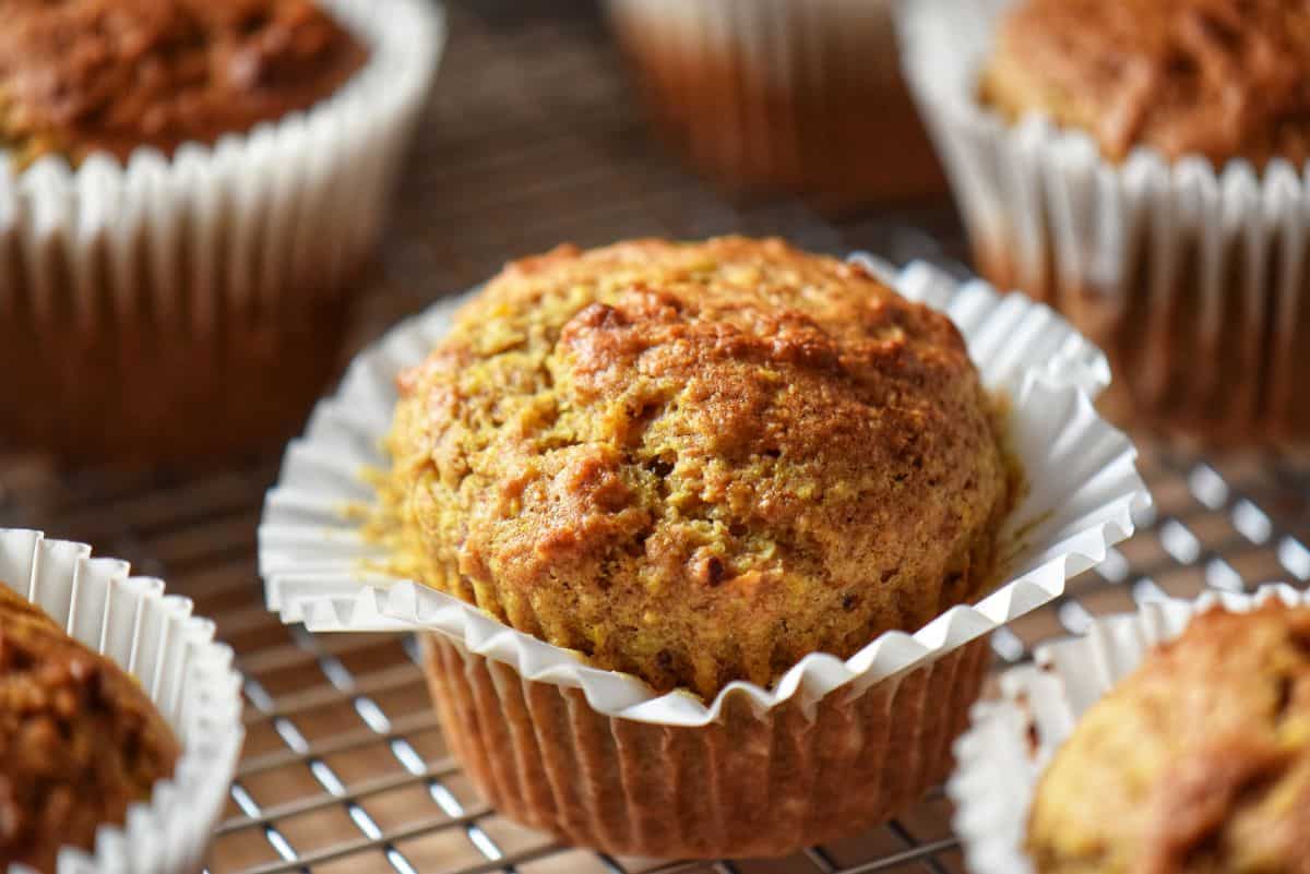 Freshly baked healthy orange muffins with dates and whole wheat flour on a cooling rack.
