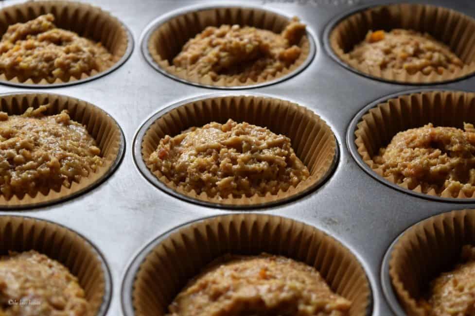 The orange date muffin batter has been portioned into the muffin cups.