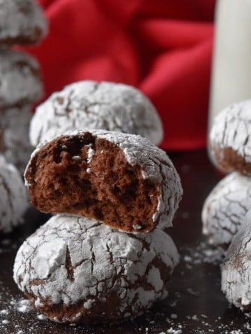 A stack of 3 crinkle cookies nest to a bottle of milk.