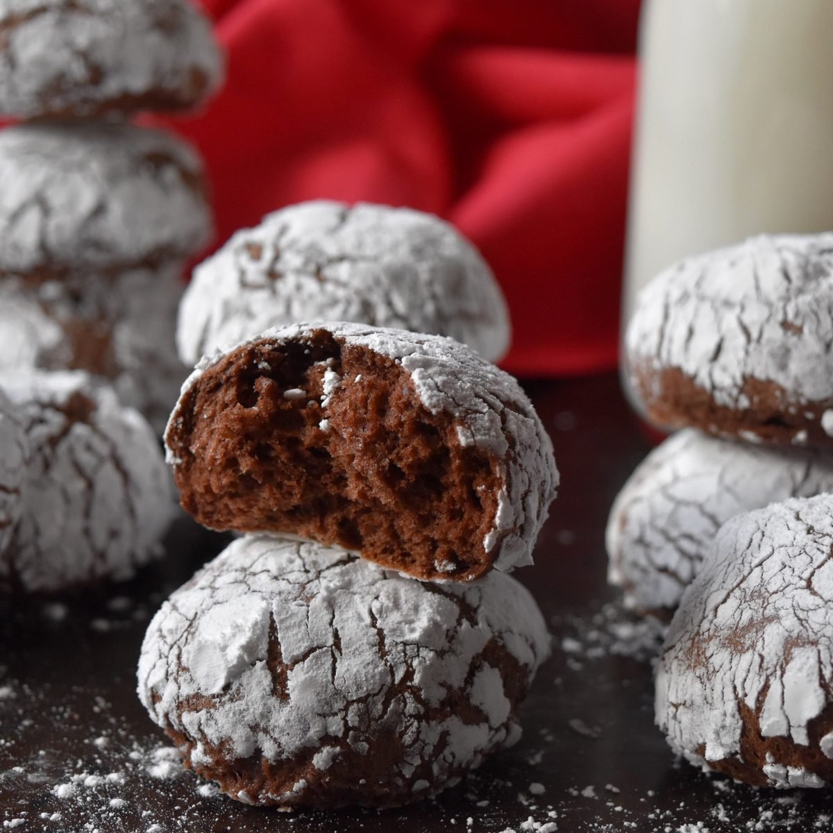 A stack of 3 crinkle cookies nest to a bottle of milk.