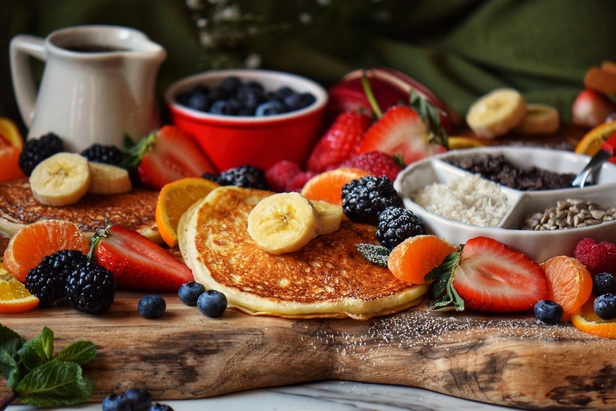 A pancake platter filled with fluffy pancakes, fruit and other toppings.