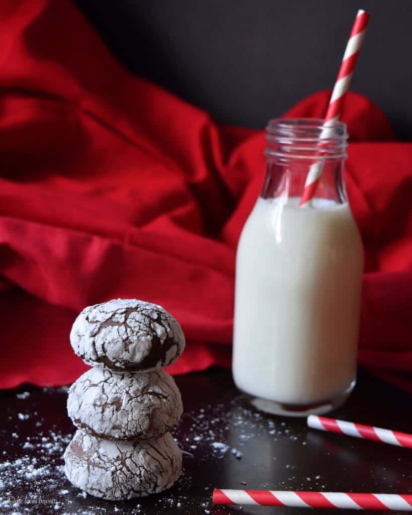 A stack of Italian Chocolate Spice Cookies with a bottle of milk in the background.