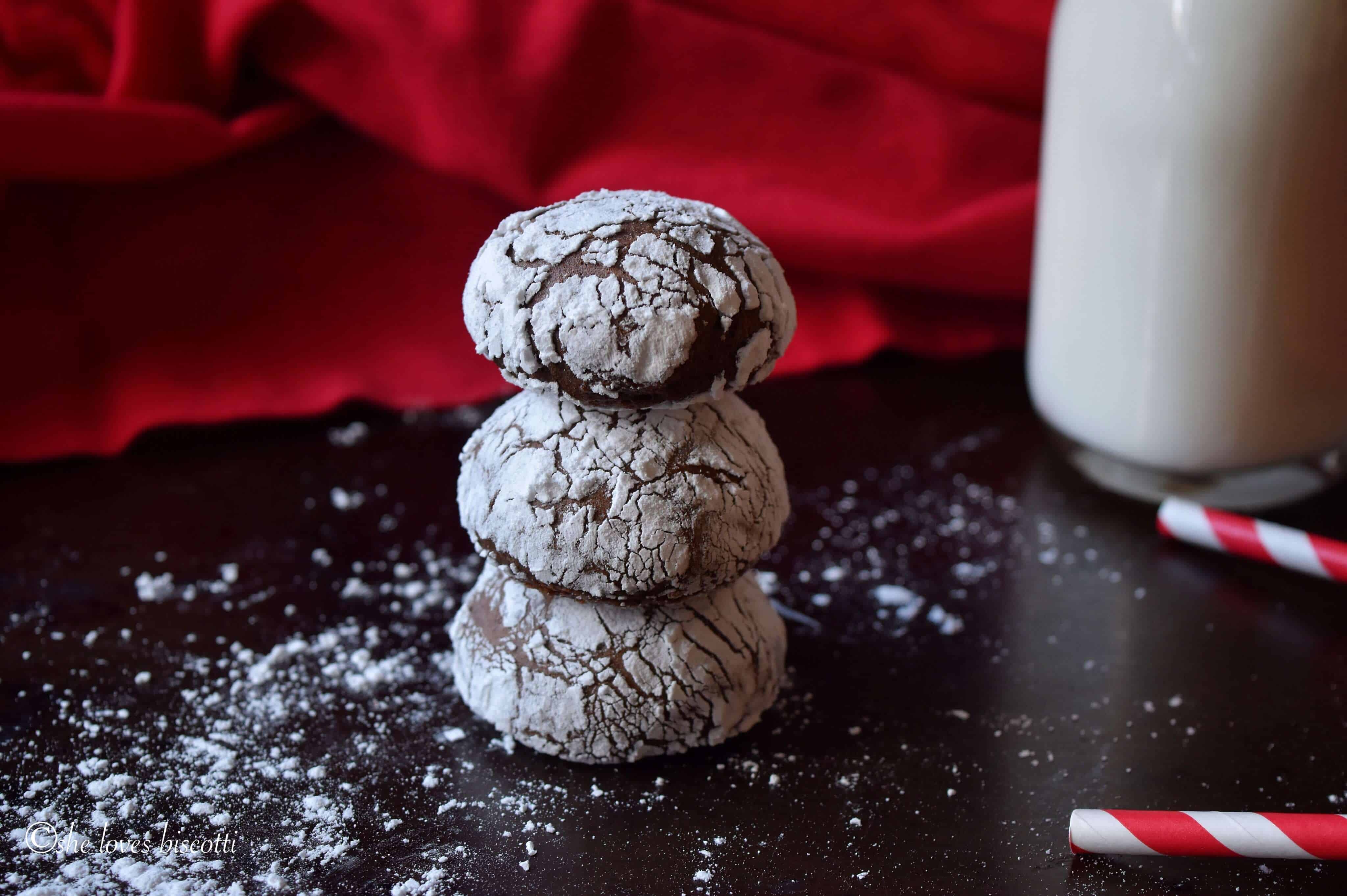 A stack of three Italian Chocolate Cookies with a bottle of milk in the background.