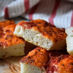 Square pieces of Italian Homemade pizza stacked on a dish.