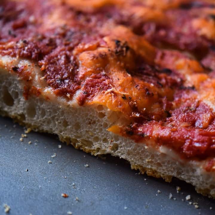 A slab of sliced pizza with tomato sauce.