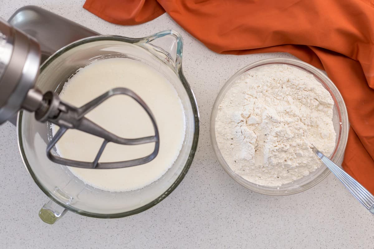 A bowl of the dry ingredients next to a bowl of a stand mixture filled with the wet ingredients.