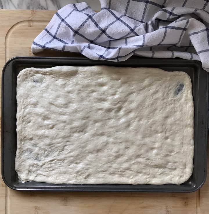 Pizza dough stretched in a sheet pan.