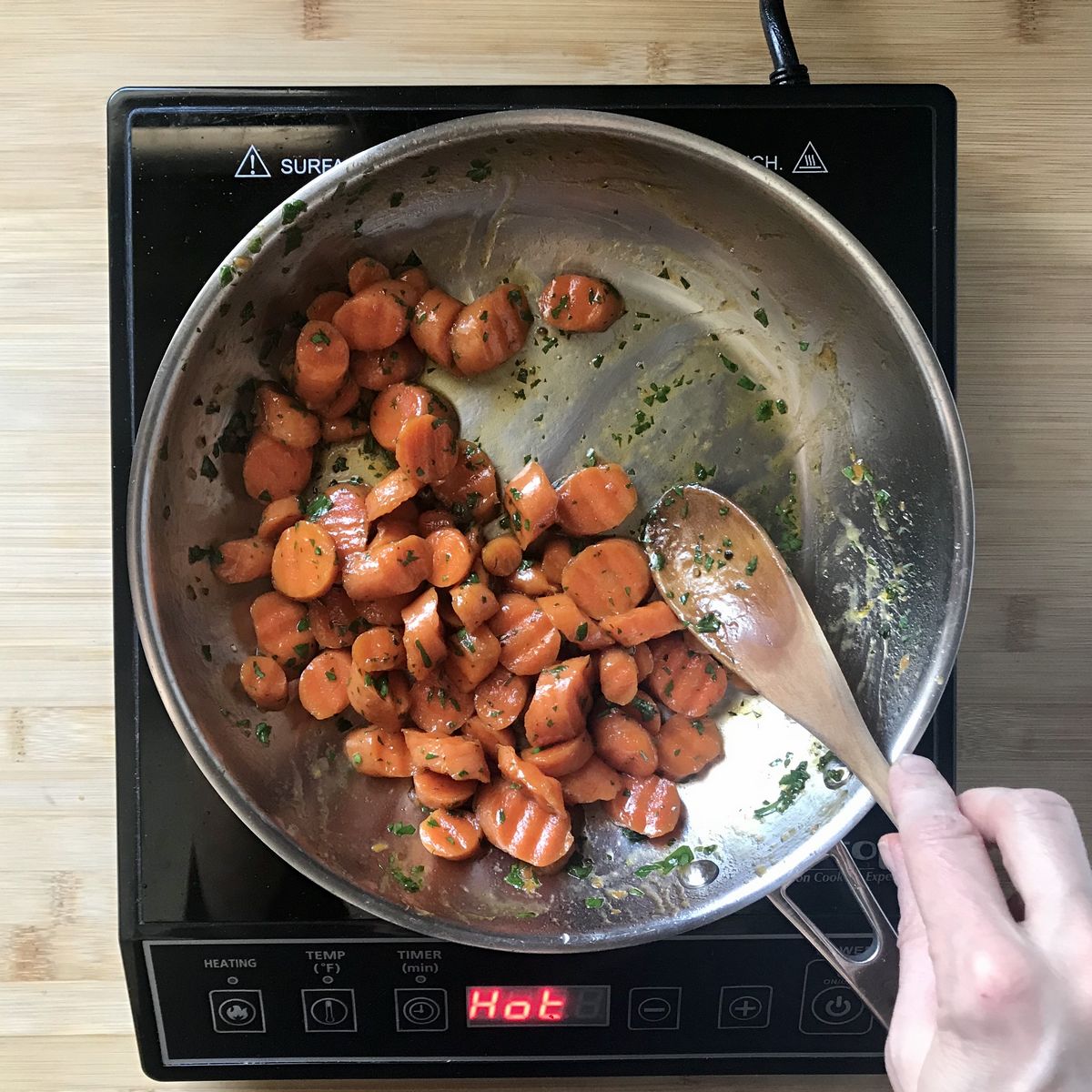 Chopped Italian parsley added to glazed carrots in a pan.
