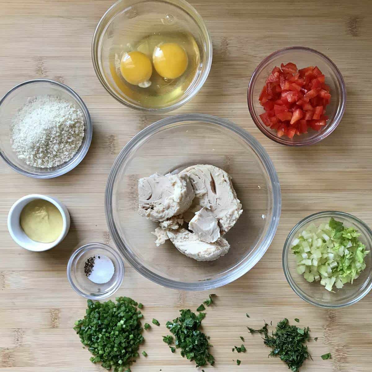 All the ingredients to make tuna croquettes are prepped on a wooden board.