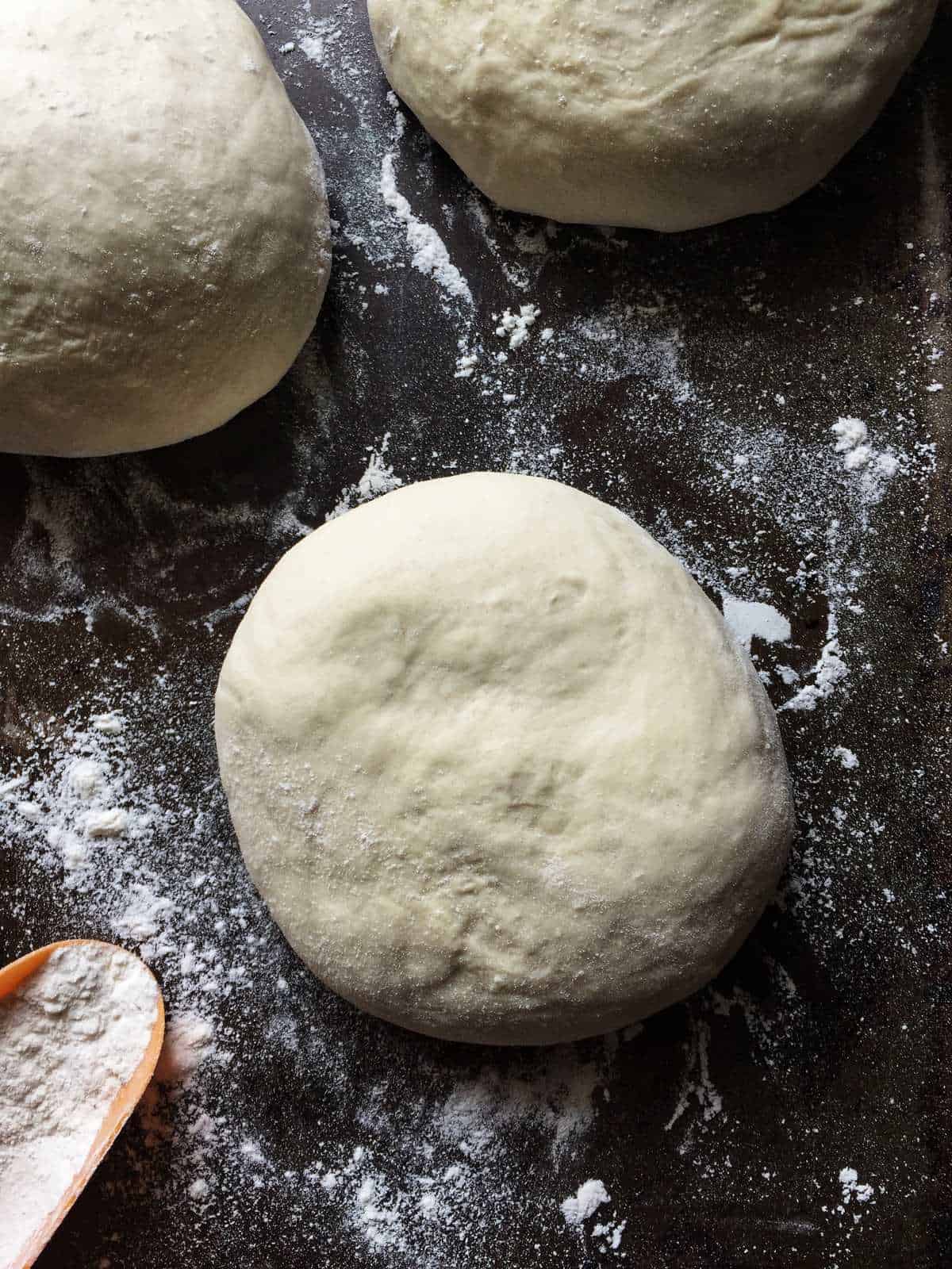 An overhead shot of pizza balls on a surface covered with flour.