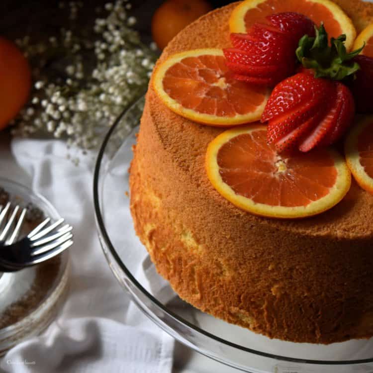 Strawberries and orange slices atop a cake.