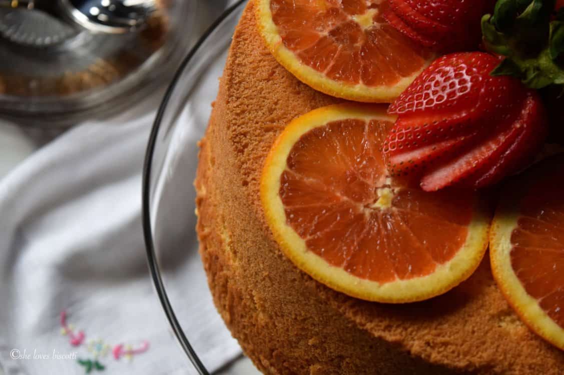 An overhead photo of sliced oranges and a strawberry atop a cake.