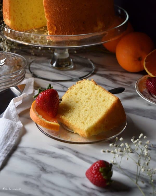 A slice of cake served with some strawberries.