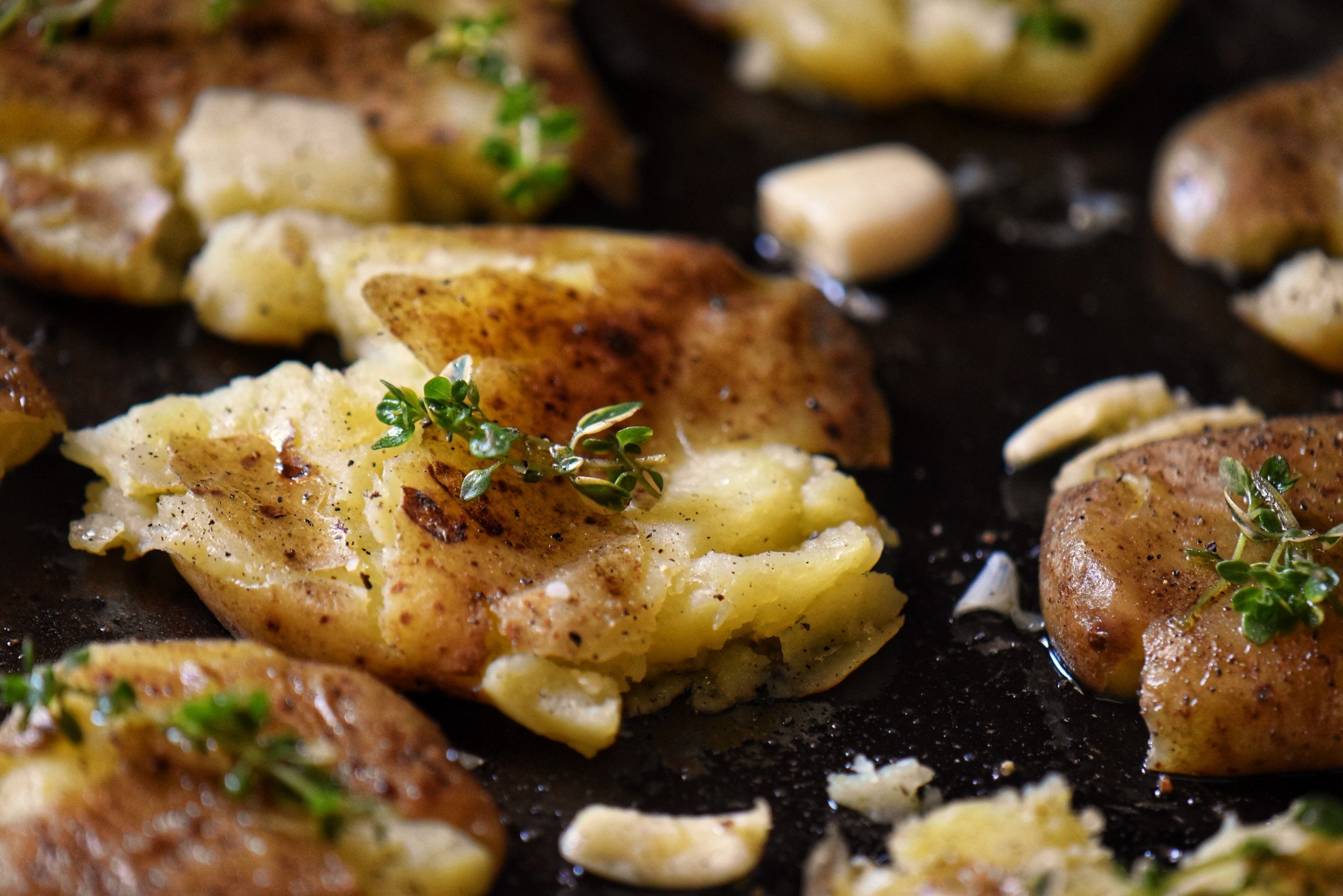 Creamer potatoes garnished with thyme sprigs on a sheet pan.
