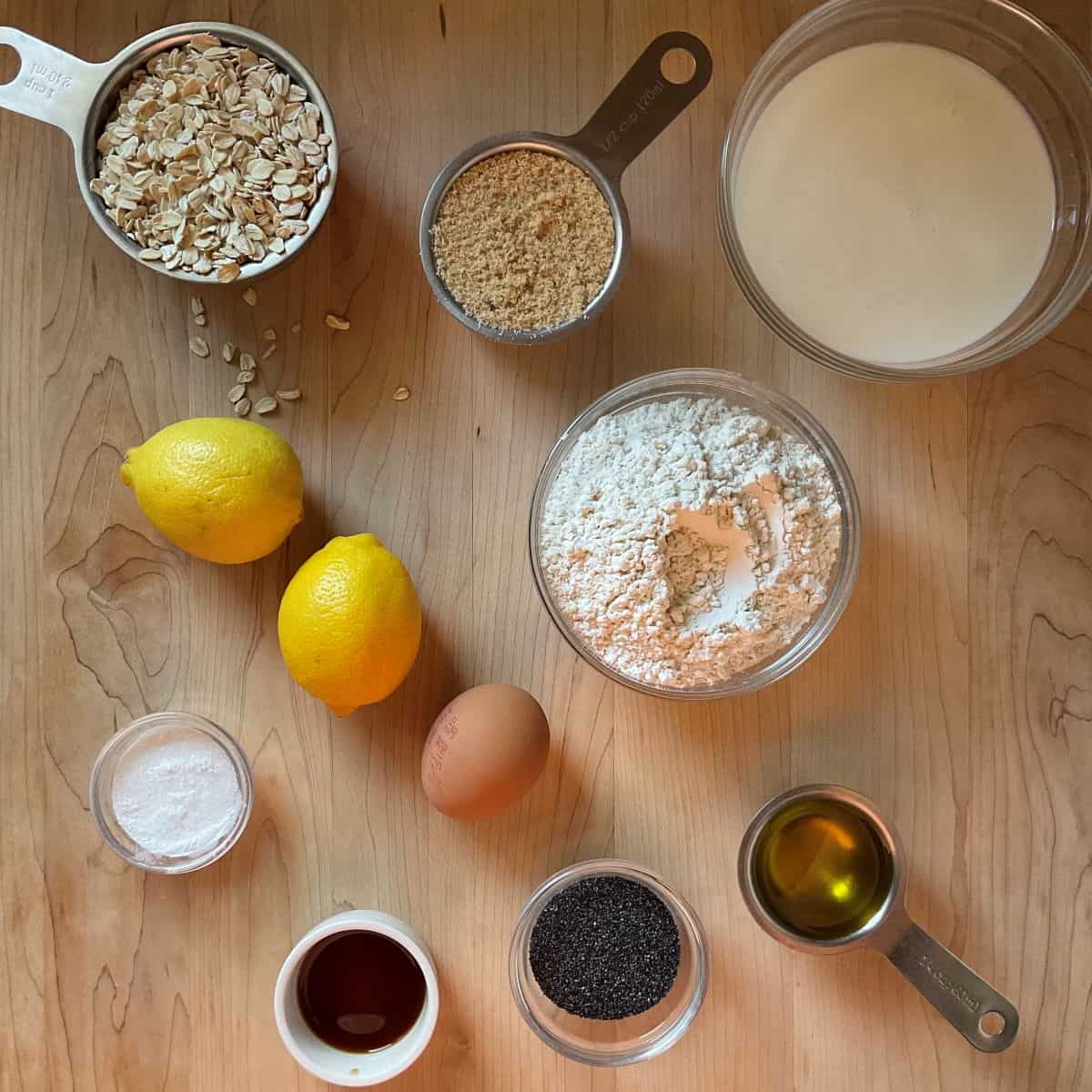 Ingredients to amke lemon poppy seed muffins on a wooden table.