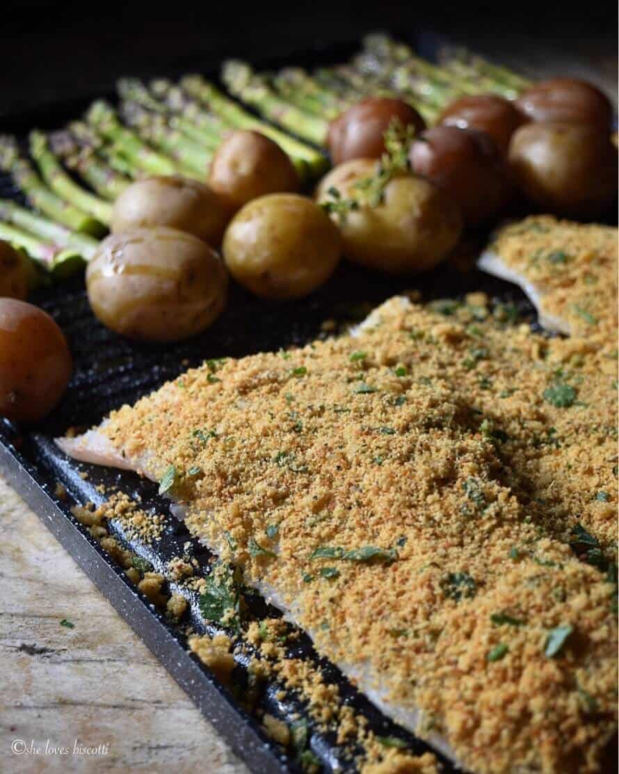 A sheet pan with the cod fish, potatoes and asparagus ready to be baked.