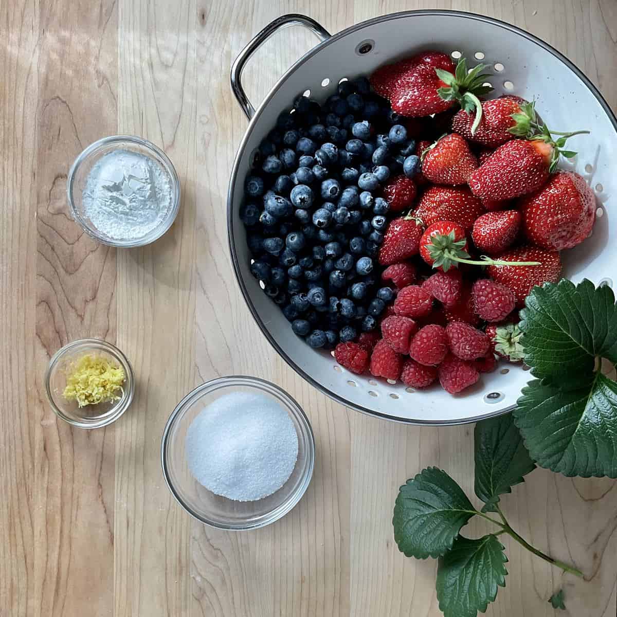 Ingredients to make a berry filling for a crostata on a wooden table.