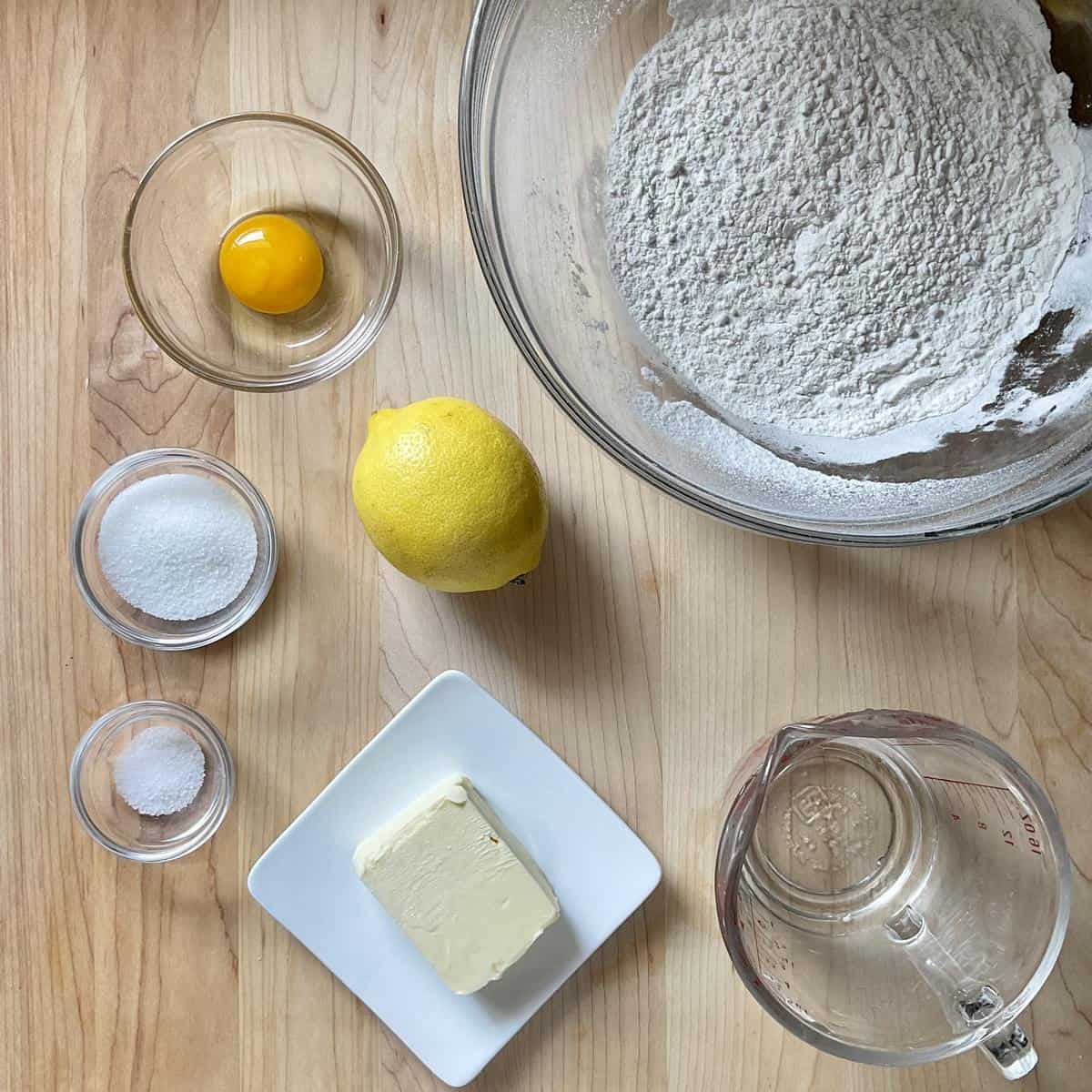 Ingredients to make a pasta frolla for a crostata on a wooden table.