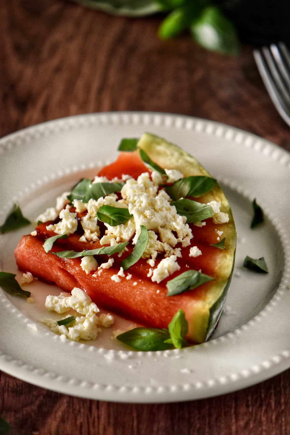 Grilled watermelon steaks on white plates..