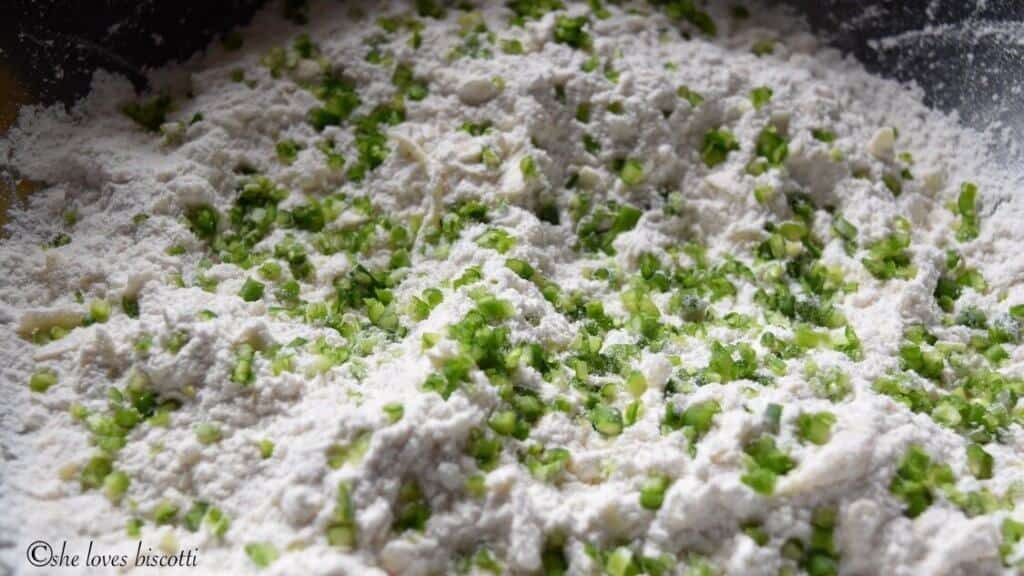 Minced garlic scapes being incorporated with the dry ingredients.