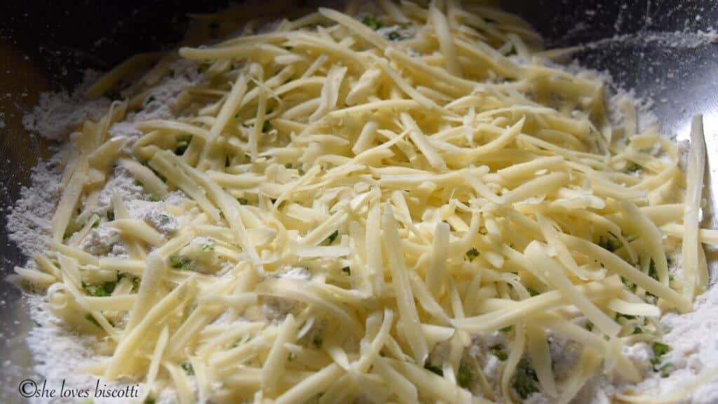 Incorporating the grated cheese in the mixture for the cheese biscuits.