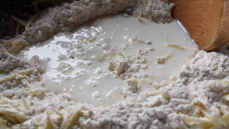 A well formed in the dry ingredients of the cheese biscuits has been filled with buttermilk.