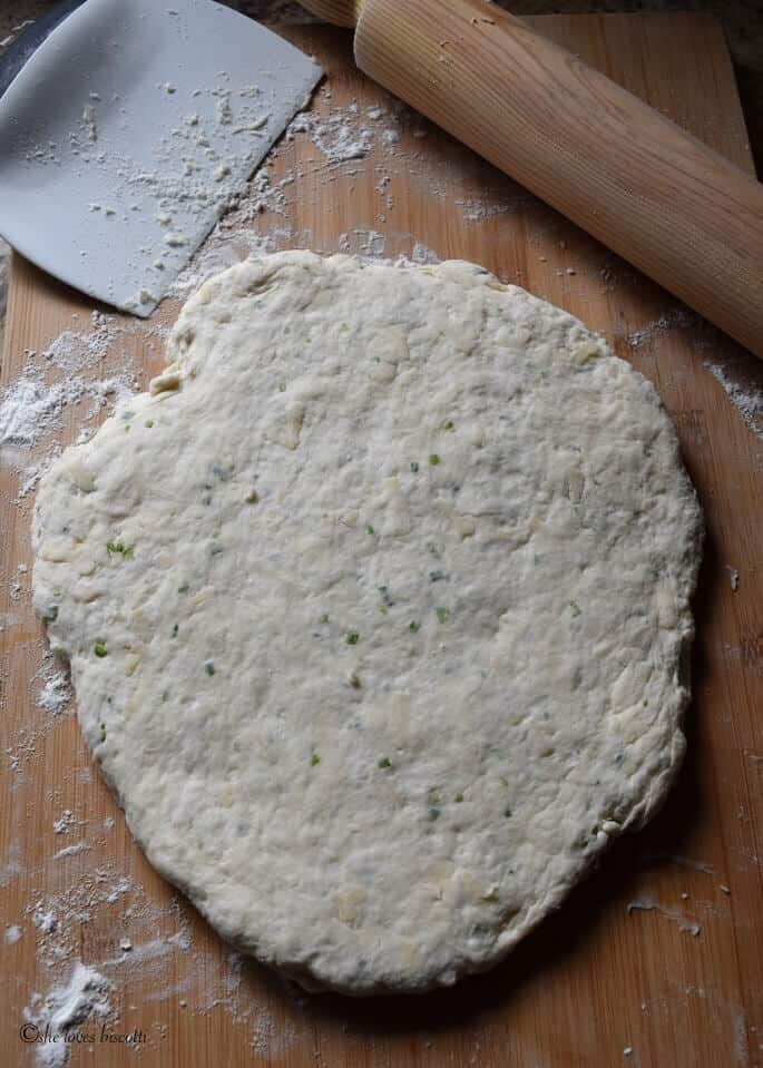 The rolled out dough of cheese biscuits on a wooden board.