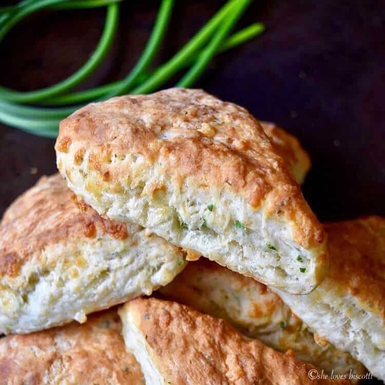 A close up of garlic scapes cheese biscuits piled on top of each other.