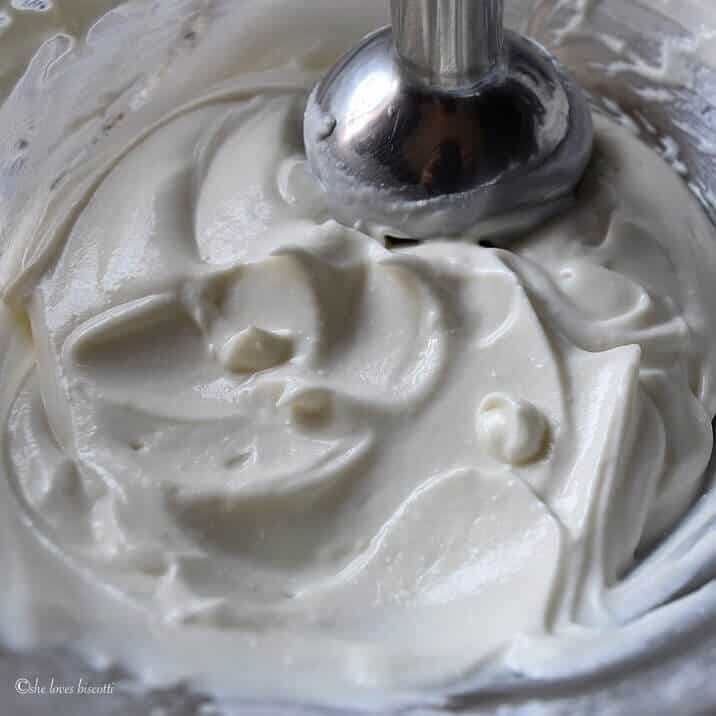 A hand held immersion blender whisking the ingredients to make a ricotta parfait. 