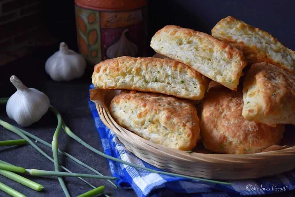 A basket of Cheese Biscuits surrounded by fresh garlic scapes.