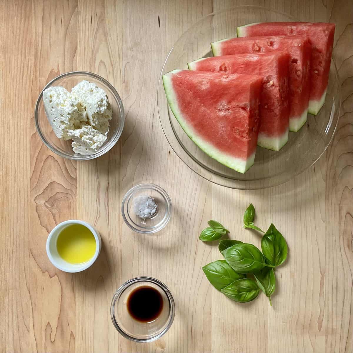 Ingredients to make grilled watermelon steaks on a wooden board.