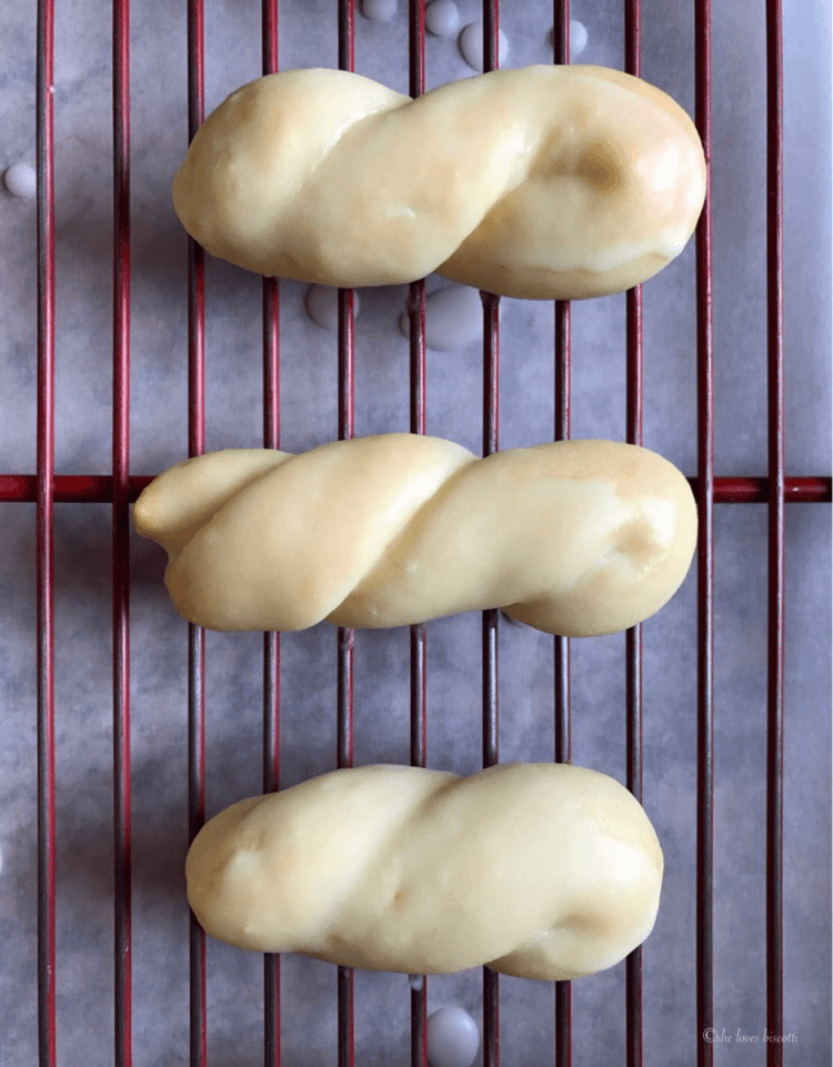 3 glazed lemon cookies on a cookie rack.