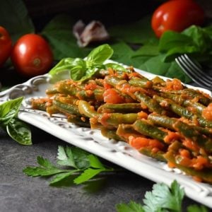 The completed dish of Italian Green Beans is plated on a white serving dish.