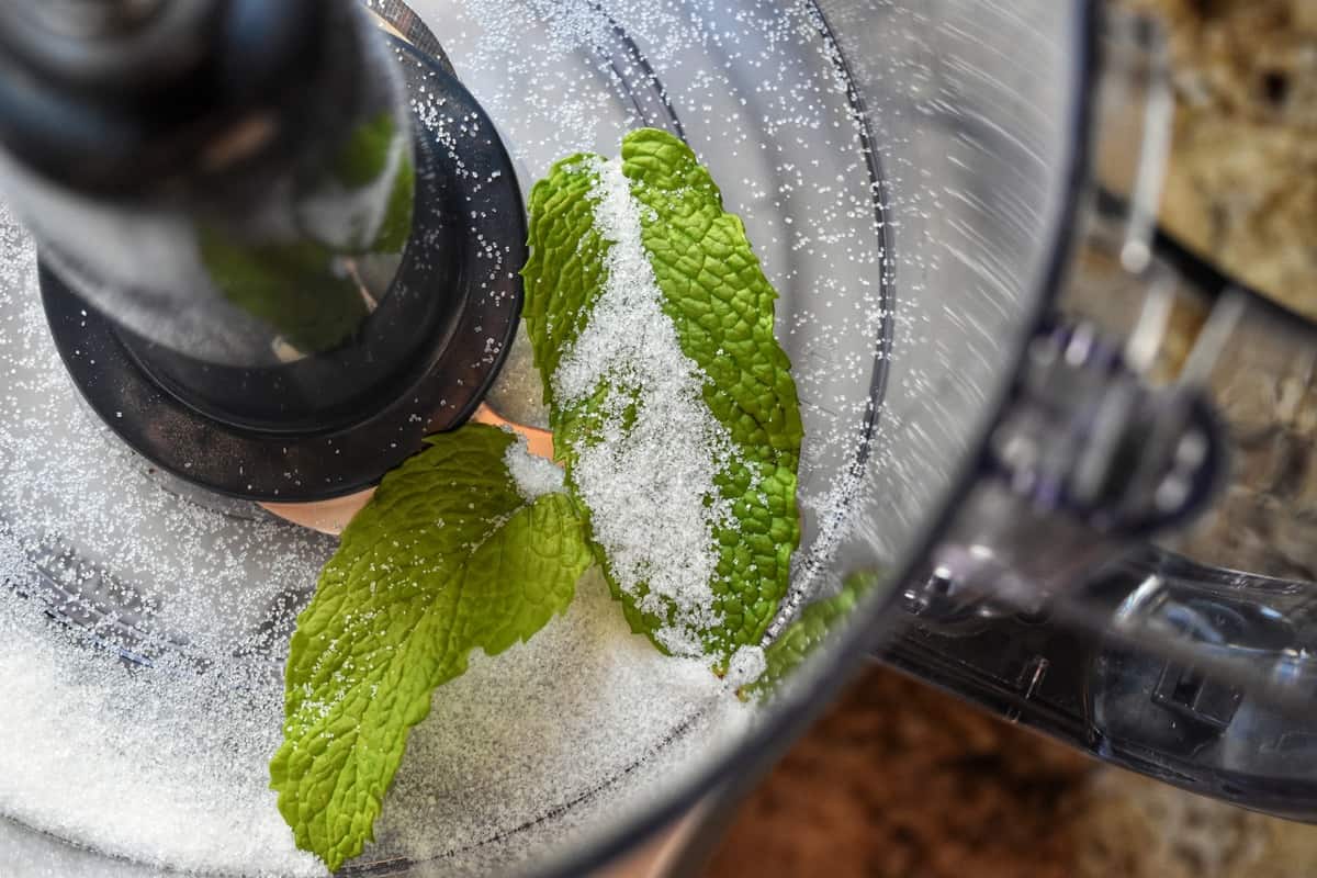 Granulated sugar and mint leaves in a food processor.