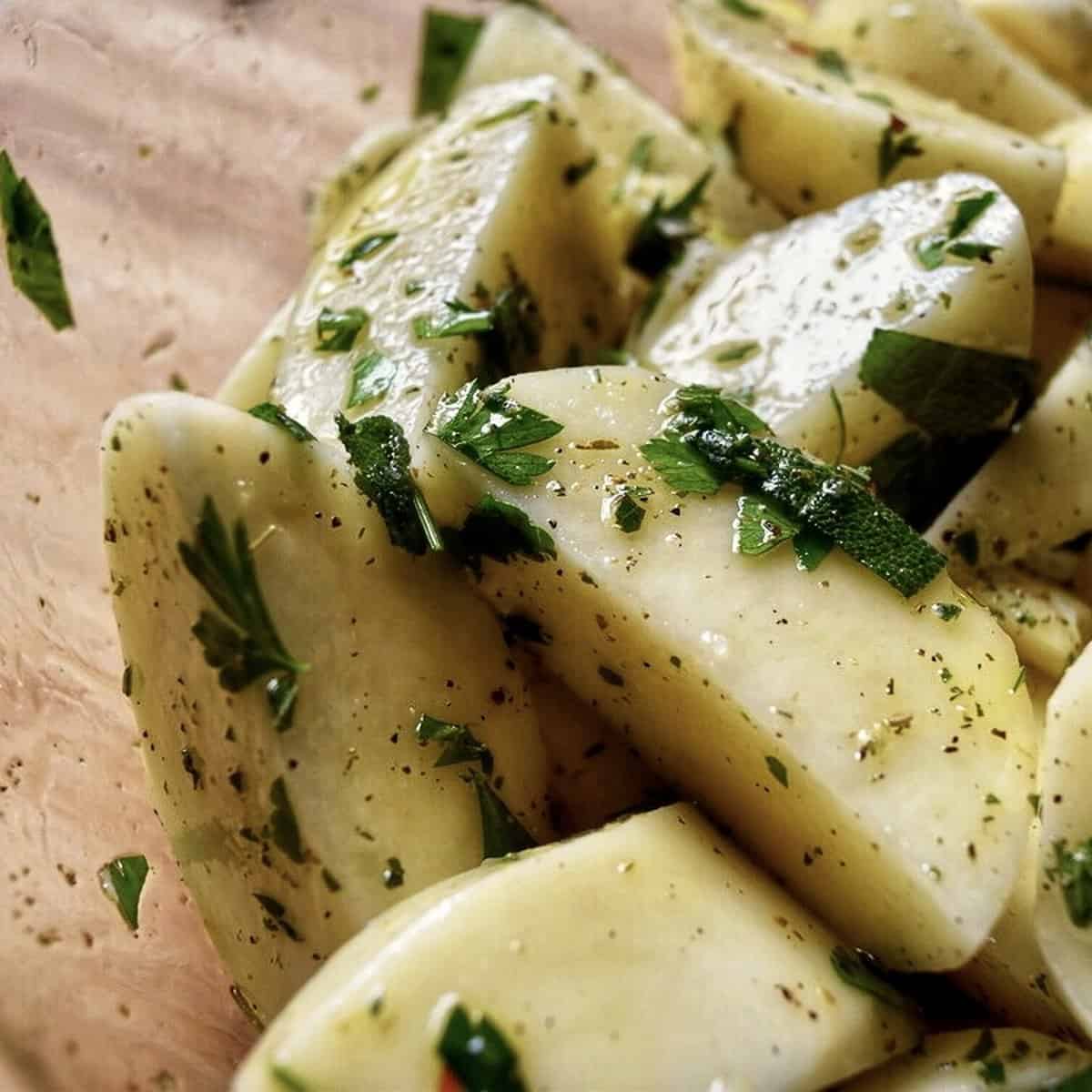 Close up shot of potatoes that are well coated with Italian herbs, spices and olive oil