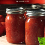 A few jars of canned whole tomatoes on a wooden board.