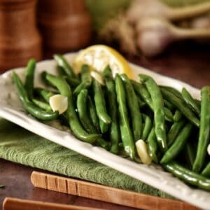 Steamed string beans with garlic on a white dish.