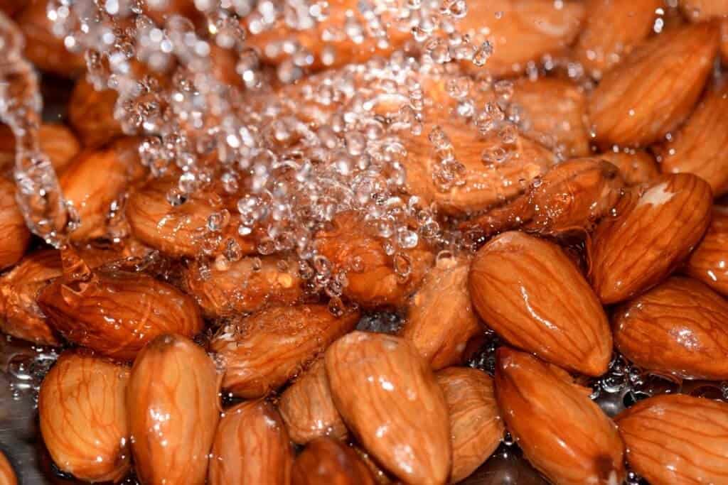 Almonds being rinsed under running water.