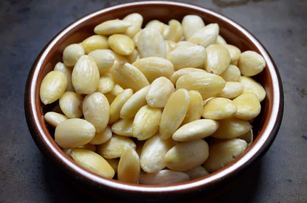 A round dish of blanched almonds is shown.