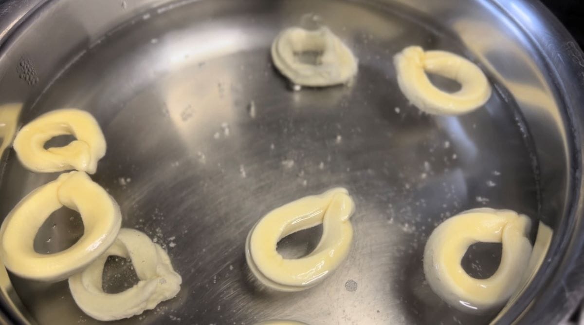 Taralli in the process of being boiled in a pot of simmering water.