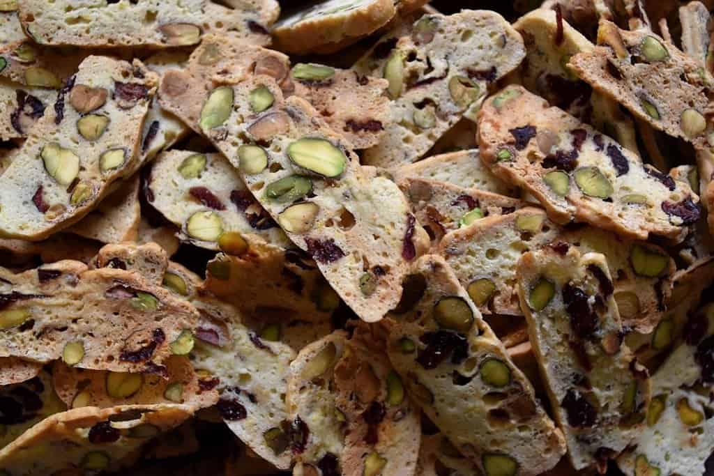 An overhead shot of dozens of colorful thin Cranberry Pistachio Biscotti