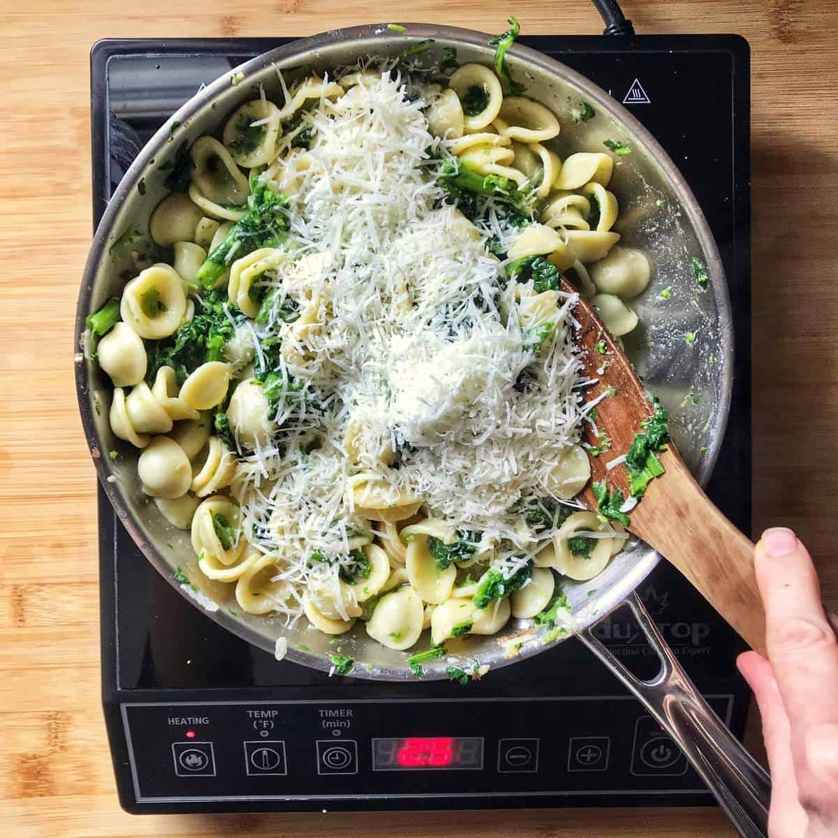 Cheese being incorporated with the broccoli rabe pasta.