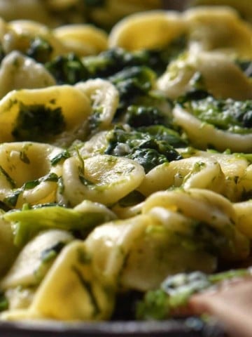 Orecchiette pasta with broccoli rabe tossed in a pan.