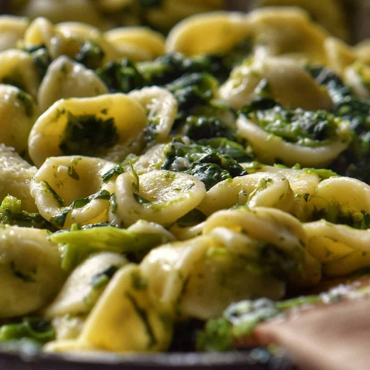 Orecchiette pasta with broccoli rabe tossed in a pan.