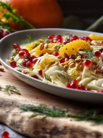 Pomegranate arils, orange sections and thinly sliced fennel in a serving platter.